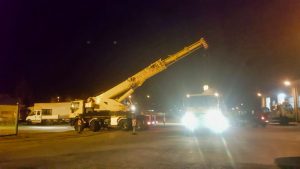 Camion gru illuminato di notte in un parcheggio.