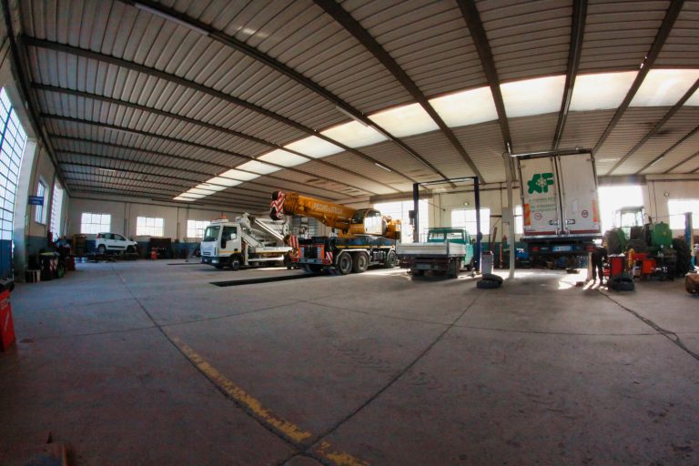 Officina con camion e attrezzature meccaniche all'interno.
