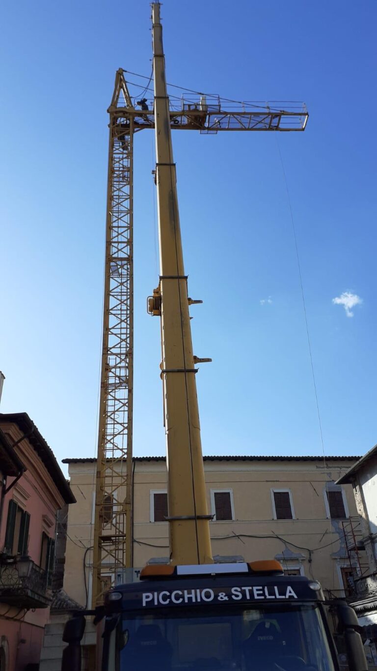 Gru gialla alta con operai al lavoro.