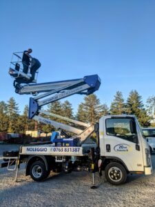 Camion con piattaforma elevatrice e persona in alto.